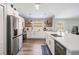 Bright kitchen features stainless steel appliances, white cabinets, quartz countertops, floating shelves, and hardwood floors at 25324 Lexington Oaks Blvd, Wesley Chapel, FL 33544