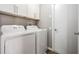 Laundry room with white front load washer and dryer and upper cabinets at 25324 Lexington Oaks Blvd, Wesley Chapel, FL 33544