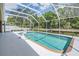 Enclosed pool with white tile deck and a serene view of the pond and lush greenery at 25324 Lexington Oaks Blvd, Wesley Chapel, FL 33544