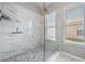 Walk-in shower featuring marble-style tile surround and herringbone tile shower floor at 25324 Lexington Oaks Blvd, Wesley Chapel, FL 33544
