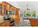 Modern kitchen features stainless steel appliances, wooden cabinets, granite countertop, and view of outdoor living space at 294 Kentucky Ave, Crystal Beach, FL 34681