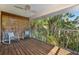 Outdoor patio featuring wood decking, ceiling fan, and comfortable chairs with view of mature palm trees at 294 Kentucky Ave, Crystal Beach, FL 34681