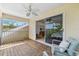 Relaxing screened in patio with wood floors, ceiling fan, and comfortable seating overlooking lush tropical foliage at 294 Kentucky Ave, Crystal Beach, FL 34681
