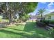 Well-maintained backyard featuring a wooden fence, mature trees, and views of the adjacent pond at 29737 Fog Hollow Dr, Wesley Chapel, FL 33543
