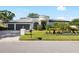 Beautiful white single-story home with a well-manicured lawn and a three car garage at 30247 Fairway Dr, Wesley Chapel, FL 33543