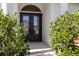 Close-up of the elegant double front doors framed by lush greenery, offering a grand entrance to the home at 30247 Fairway Dr, Wesley Chapel, FL 33543