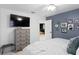 A lovely bedroom features a dresser, TV, ceiling fan, blue accent wall and black and white photos at 3325 W Wallcraft Ave, Tampa, FL 33611