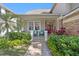 Inviting front porch featuring outdoor seating, lush landscaping, and a brick pathway leading to a striking red front door at 3325 W Wallcraft Ave, Tampa, FL 33611