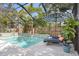 Inviting screened-in pool area featuring lounge chairs, an umbrella, and well-maintained landscaping at 3325 W Wallcraft Ave, Tampa, FL 33611