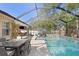 A luxurious screened-in pool area with a waterfall feature, lounge area, and an outdoor dining space at 3325 W Wallcraft Ave, Tampa, FL 33611