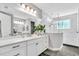 Bright bathroom featuring dual sinks, white cabinets, marble countertops, and a glass-enclosed shower at 4251 W Roland St, Tampa, FL 33609