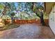 Spacious backyard featuring a brick-paved patio, wooden fence, and mature trees for shade at 4926 Camellia S Way, St Petersburg, FL 33705