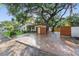 Home exterior featuring a driveway, large shade trees, lush green lawn, and a wood privacy fence at 4926 Camellia S Way, St Petersburg, FL 33705