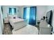 Cozy bedroom with a white bed, hardwood flooring, blue curtains, and natural light from the window at 5151 22Nd N Ave, St Petersburg, FL 33710