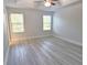 Bedroom featuring light gray wood-look flooring, two windows, and a ceiling fan at 5509 Cumberland Star Ct, Lutz, FL 33558