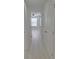 Hallway with gray wood floors leading to a bedroom with a ceiling fan and natural light at 5509 Cumberland Star Ct, Lutz, FL 33558
