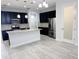 Bright kitchen featuring dark cabinetry, stainless steel appliances, a central island, and light-colored tile flooring throughout at 5509 Cumberland Star Ct, Lutz, FL 33558