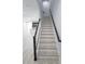 Bright staircase with wood-look tile and dark wood railings leading to an open kitchen and living area at 5509 Cumberland Star Ct, Lutz, FL 33558