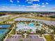 Aerial view of the luxurious community pool, clubhouse, and lake with palm trees at 7209 Meeting House Ln, Apollo Beach, FL 33572