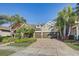 Beautiful home featuring a three-car garage, paver driveway, and tropical palm trees at 7209 Meeting House Ln, Apollo Beach, FL 33572