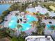 Aerial view of luxurious community pool area with ample lounge seating, lush palms, and a winding waterslide at 7209 Meeting House Ln, Apollo Beach, FL 33572