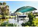 Waterfront view featuring a covered boat lift, private dock, and two-story home with ample outdoor seating at 754 Seminole Blvd, Tarpon Springs, FL 34689