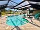 Large, screened-in pool surrounded by pavers with outdoor seating and a view of lush greenery at 754 Seminole Blvd, Tarpon Springs, FL 34689