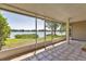 Enclosed lanai featuring tiled flooring, screened windows, and tranquil views of the surrounding landscape and lake at 8719 Lake Place Ln, Tampa, FL 33634