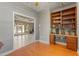 Well-lit office featuring hardwood floors and custom shelves, seamlessly connecting to outdoor living at 8933 Crescent Forest Blvd, New Port Richey, FL 34654