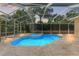 Sparkling in-ground pool and spa with a screened enclosure and travertine tile deck at 8933 Crescent Forest Blvd, New Port Richey, FL 34654