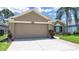 A home with a two-car garage, desert landscaping, a brick-lined walkway, and verdant lawn at 2452 Big Pine Dr, Holiday, FL 34691
