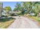 Backyard view of covered parking area, small shed, and mature trees with a paved driveway at 1025 W Berry Ave, Tampa, FL 33603