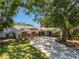 Single-story home with brick accents, a covered carport, mature landscaping, and a well-maintained lawn at 10314 Lake Carroll Way, Tampa, FL 33618