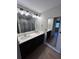 Bathroom featuring a double sink vanity, an LED mirror, wood-look tile, and a walk-in shower in the background at 12021 Coleman Ave, Port Charlotte, FL 33981