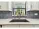 Kitchen sink with white countertop, herringbone backsplash and window at 1236 Abbey Crescent Ln, Clearwater, FL 33759