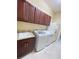 This laundry room has brown cabinets, a sink, a washer and dryer, and a full size refrigerator at 12619 50Th E Ct, Parrish, FL 34219