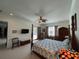 Bright main bedroom with a four-poster bed, ceiling fan, and sliding glass doors to the pool at 12619 50Th E Ct, Parrish, FL 34219