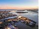Breathtaking aerial view of a waterfront home with stunning water views and lush landscaping at sunset at 12650 7Th E St, Treasure Island, FL 33706