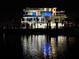 An eye-catching modern home at night, set against the water with reflective lights at 12650 7Th E St, Treasure Island, FL 33706