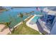 An aerial view of a stunning pool area with palm trees, blue lounge chairs, and waterfront views, perfect for relaxation at 12650 7Th E St, Treasure Island, FL 33706