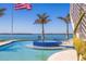 A stunning in-ground pool with blue tile accents and swaying palms offers a tranquil oasis by the waterfront at 12650 7Th E St, Treasure Island, FL 33706
