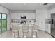 Bright white kitchen with stainless steel appliances, a center island with bar seating, and sliding glass doors to the backyard at 13434 Tropical Breeze Way, Hudson, FL 34669