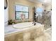 Bright bathroom with soaking tub, decorative stained-glass window, and frameless shower enclosure at 1509 Amarone Pl, Lutz, FL 33548