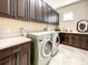Bright laundry room with custom cabinets, countertops, sink, and modern washer and dryer at 1509 Amarone Pl, Lutz, FL 33548
