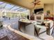 Inviting outdoor patio with comfortable seating, a stone fireplace, TV, and a view of the pool at 1509 Amarone Pl, Lutz, FL 33548