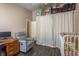 Bedroom featuring wood floors, a sitting area, and a crib with decorations at 15856 49Th N St, Clearwater, FL 33762