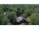 Aerial view showcases a home and outbuilding nestled amongst lush greenery and mature trees at 16420 Iola Woods Trl, Dade City, FL 33523