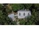 Aerial view features a sprawling home with a metal roof, surrounded by lush greenery at 16420 Iola Woods Trl, Dade City, FL 33523