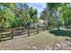 Picturesque backyard with a wooden fence, mature trees, and a partial view of the charming white home at 16420 Iola Woods Trl, Dade City, FL 33523