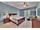 Comfortable bedroom with blue walls, ceiling fan, carpet, and a seating area with a cozy chair at 16420 Iola Woods Trl, Dade City, FL 33523